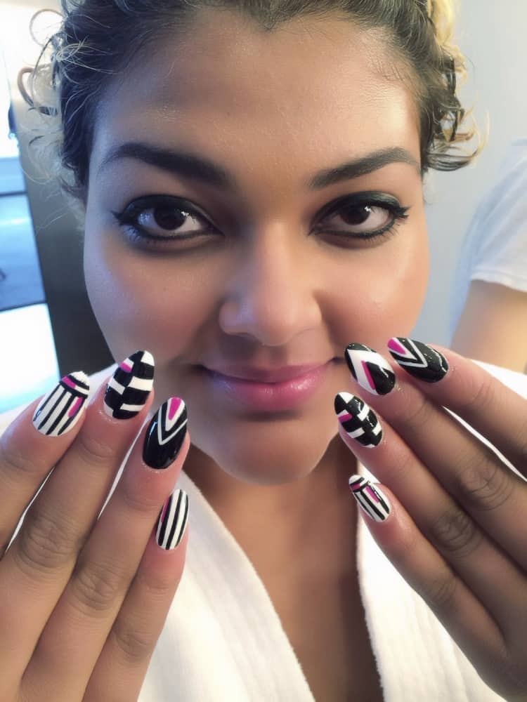 Nail stylist Elle used a Dermelect Opulence (white) and Provocative (pink) on LeeAnn and Tay. She also used acrylic paint to color block and outline nails in black. 